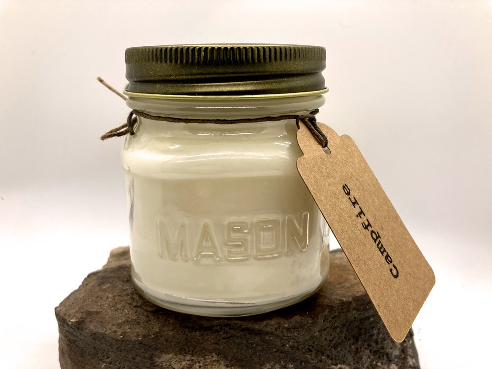 
                  
                    Load image into Gallery viewer, Mason Jar filled with 100 % pure soy wax candle. Campfire is the scent with a gift tag attached.
                  
                