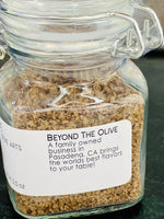 Close up of small glass jar filled with Applewood smoked sea salt. Listed information of Manufacturer Beyond The Olive, a family owned business in Pasadena, CA.
