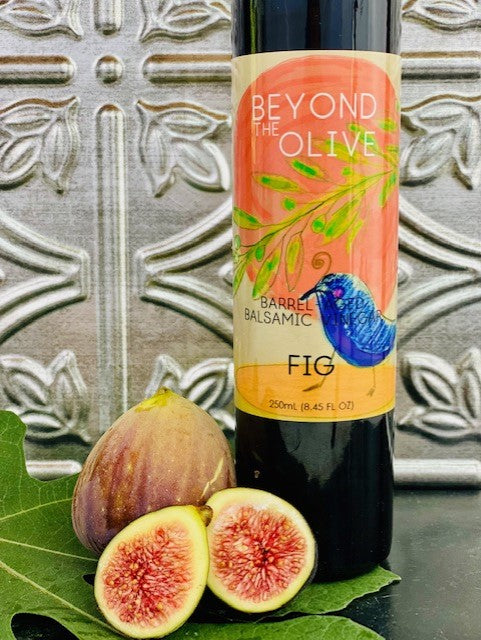 BOTTLE OF FIG BALSAMIC VINEGAR PICTURED WITH FRESH FIGS AND FIG LEAF