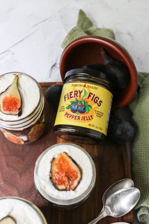 
                  
                    Load image into Gallery viewer, 11 oz. closed jar Jenkins Fiery Figs pepper jelly lays on it&amp;#39;s back surrounded by fresh whole figs. Aerial view of truffle dessert with figs, whipped cream and layers of hot pepper jam with habanero and jalapeno peppers.
                  
                