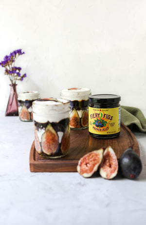 
                  
                    Load image into Gallery viewer, Fiery Figs hot pepper jam can be used for desserts as well as savory main dishes. Pictured here is a fruit truffle with slices of fresh figs, whipped cream and layers of Jenkins Jellies Fiery Figs pepper jelly. Unopened 11 oz jar with it&amp;#39;s bright yellow label and painted label - makes a statement on this dessert tray.
                  
                