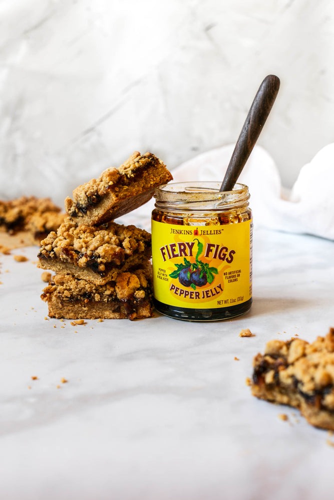 
                  
                    Load image into Gallery viewer, Opened jar of Fiery Figs hot pepper jelly with a spoon resting. This balanced sweet and spicy pepper jam with fresh figs takes this baked goods fruit bar to the next level. 
                  
                