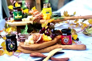 
                  
                    Load image into Gallery viewer, Jenkins Jellies sweet and spicy hot pepper jam is the perfect partner on any charcuterie or cheese board offering. Picutred here on wooden serving paddles with cubes of cheese, grapes, salami and crackers. Sprigs of fresh rosemary and autumn leaves create decoration.
                  
                