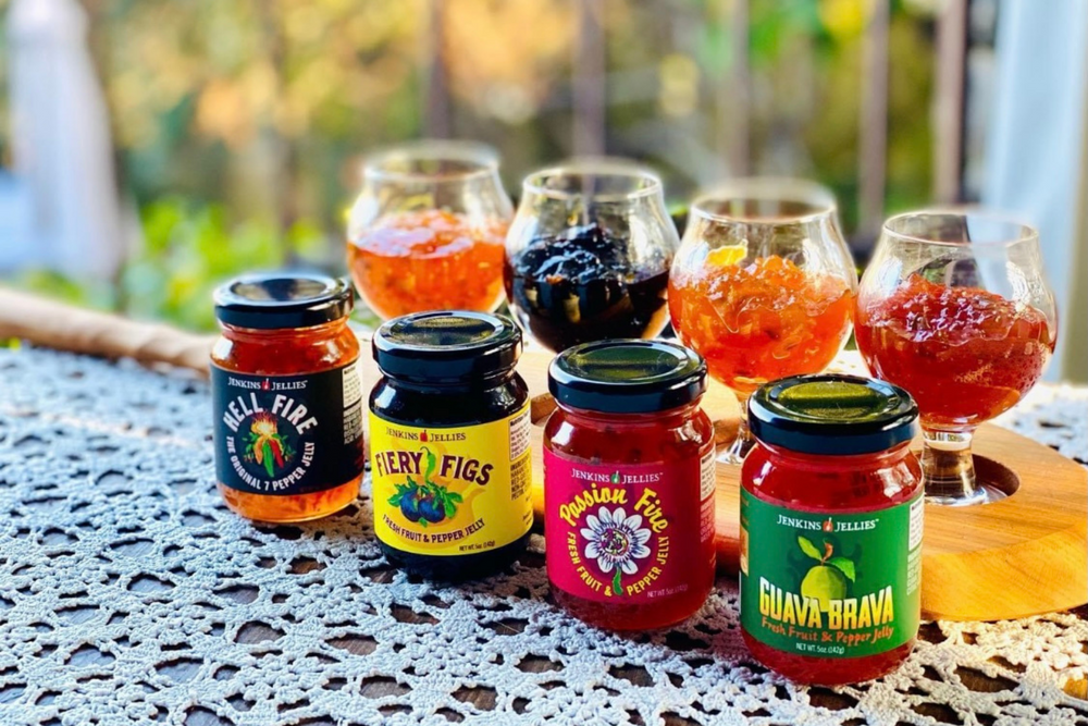 
                  
                    Load image into Gallery viewer, Jenkins Jellies hot pepper jam pictured in the 5 oz. jars and separately displayed in 4 glass jars. The rustic, heartier texture of the pepper jelly brims with jewel-like nuggets of pepper &amp;amp; fruit; creating a complex blend of seven peppers; &amp;amp; peak-season fruit purees.
                  
                